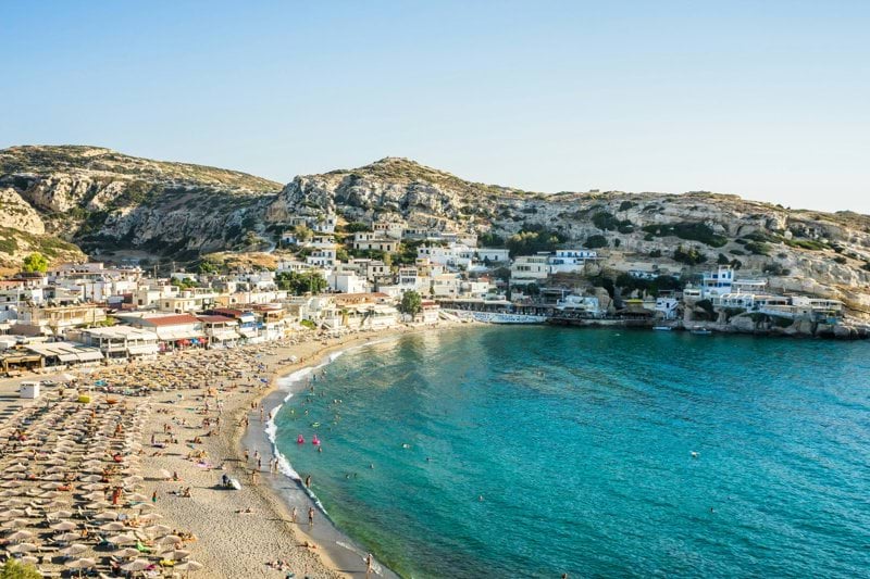 a beach with houses and a hill in the background