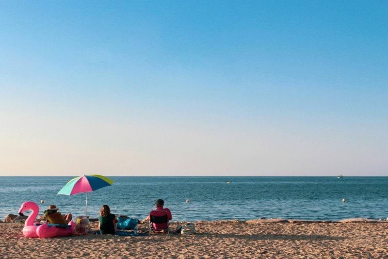 a group of people sitting on top of a sandy beach