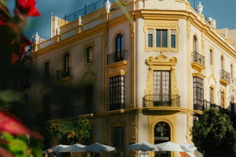 Ornate building with outdoor cafe seating in sunlight.