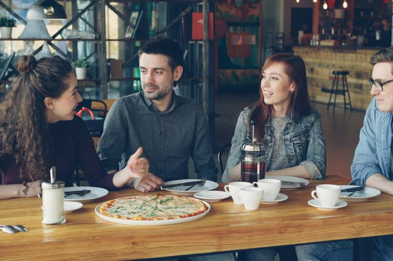 Friends enjoy pizza and conversation in a restaurant.