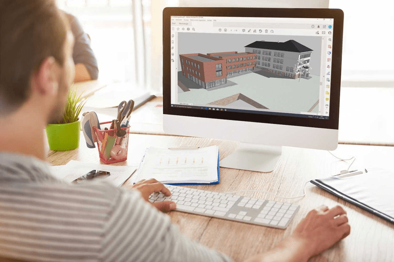 Mann sitzt am Desktop Rechner und schaut sich ein BIM Modell an