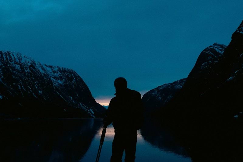 Silhouette of person standing on frozen lake at dusk