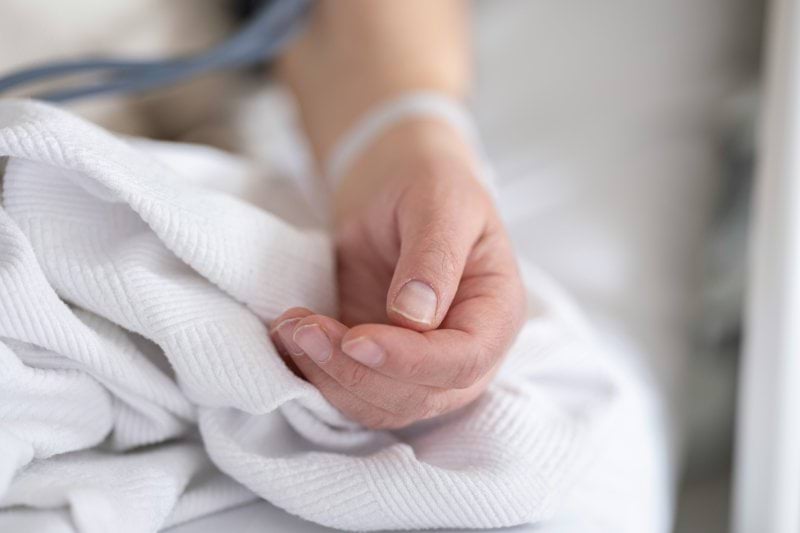 a person with a bandage on their hand sitting on a bed
