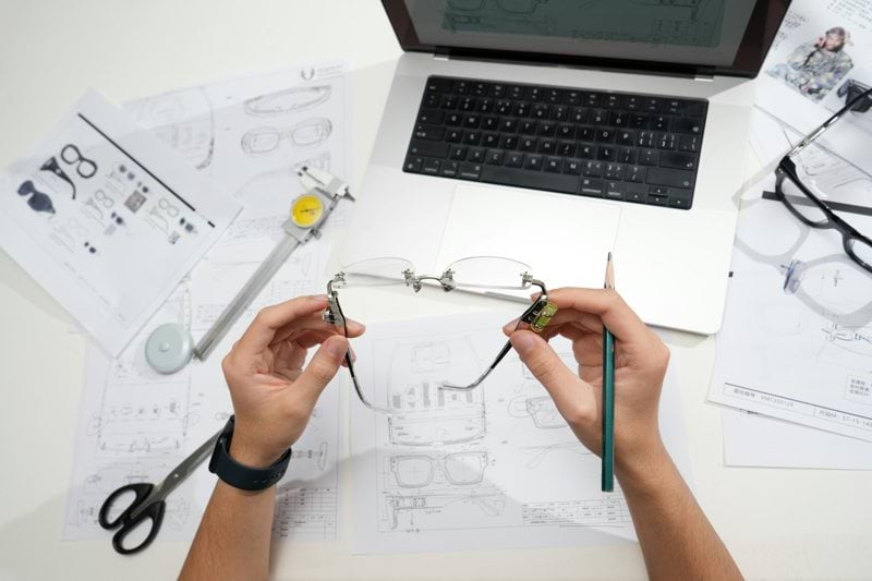 Hands holding glasses over design blueprints