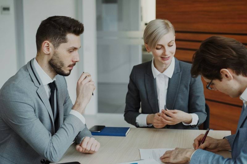 Business people signing a contract at a table.