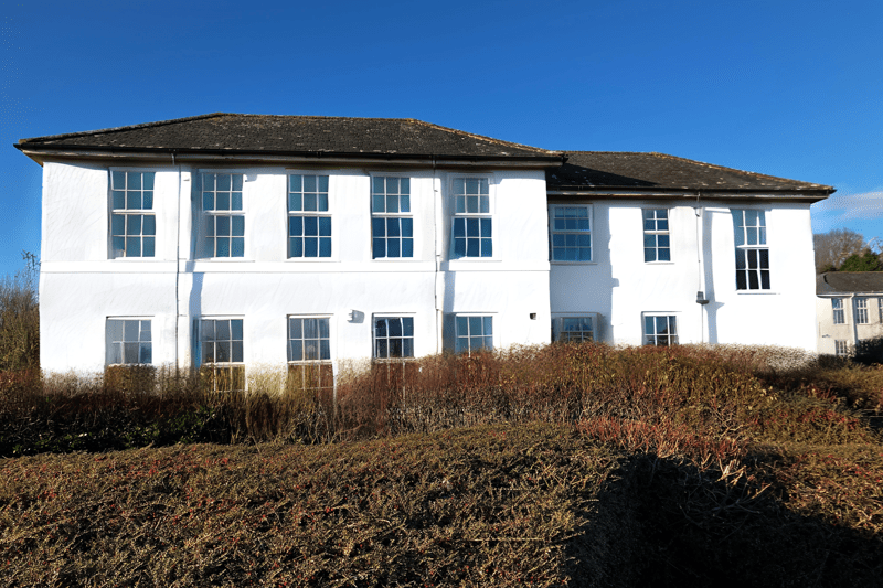 A large white Georgian office building with shrubs around it. 
