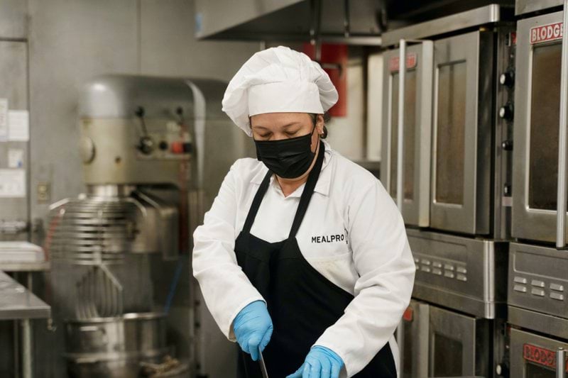 chef holding green and yellow plastic tray