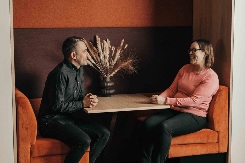Man och kvinna för ett samtal i en orange sittgrupp.