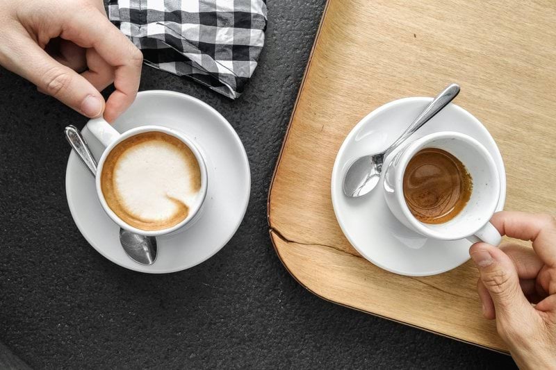 person holding white ceramic mug with brown liquid