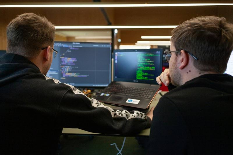 two men sitting in front of a laptop computer