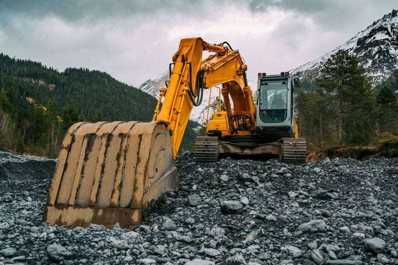 yellow and black excavator on rocky ground