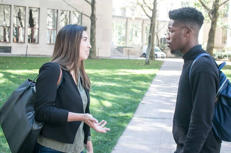 a man standing next to a woman on a sidewalk