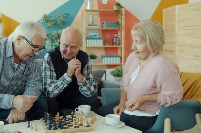 Seniors playing chess together on a sofa