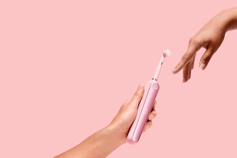person holding pink electric toothbrush