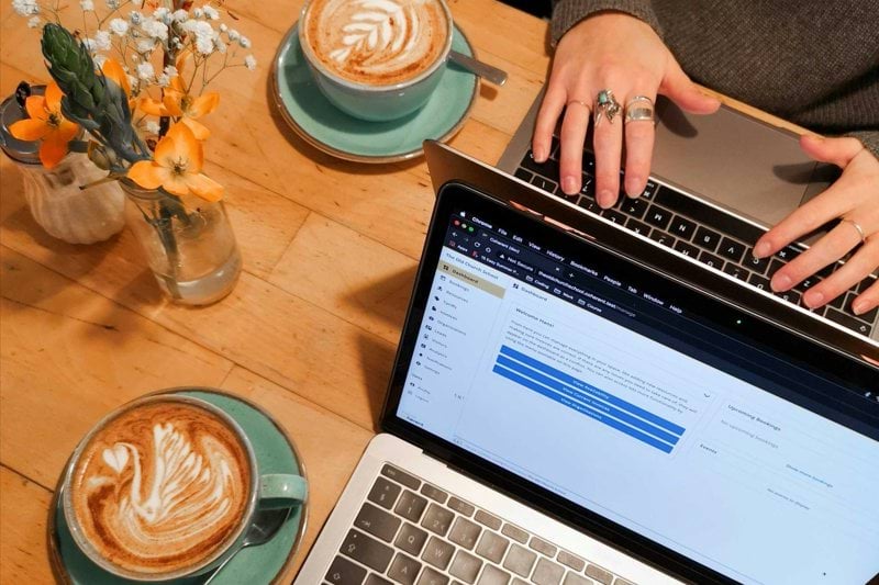 person using macbook pro on brown wooden table