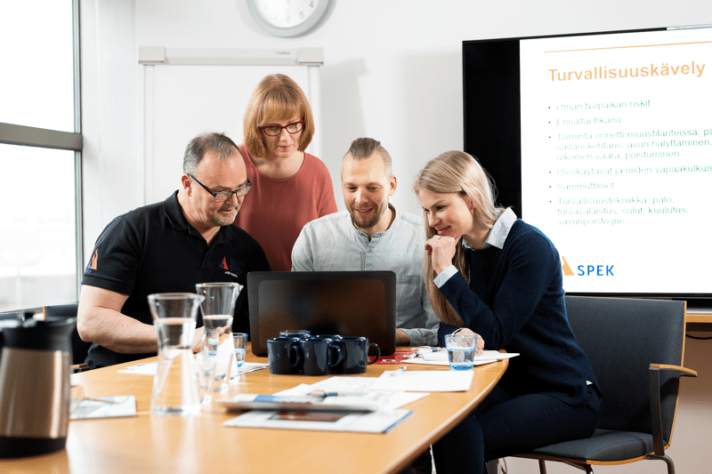 Työntekijät katsovat kokoushuoneessa saman tietokoneen näyttöä.