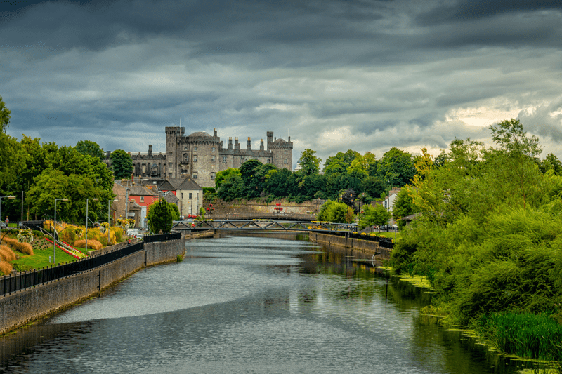 lake leading to a castle surrounded in greenery