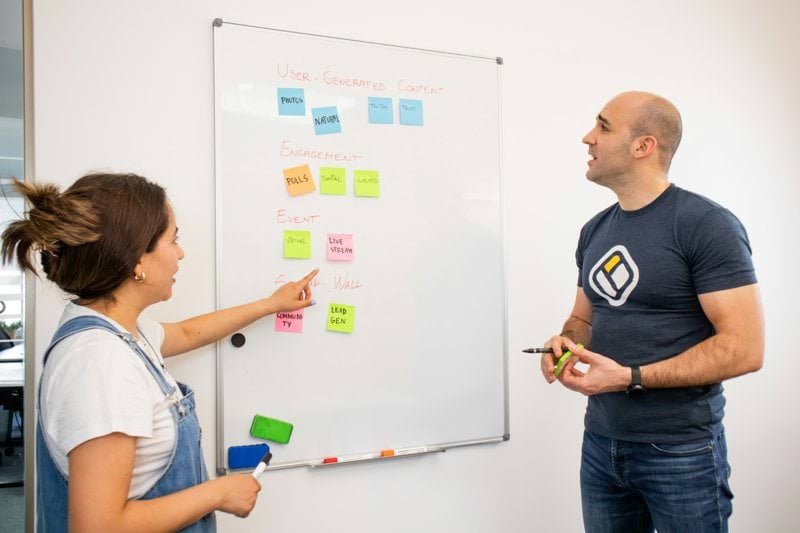a man and a woman standing in front of a white board