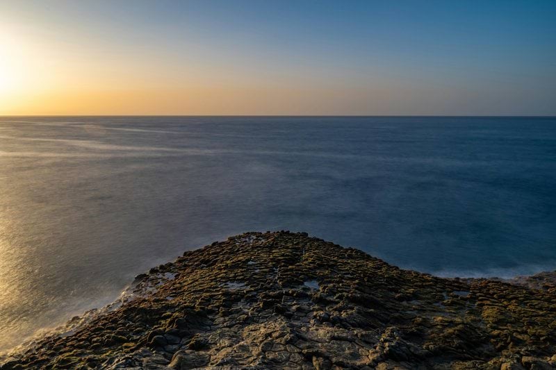 the sun is setting over the ocean on the horizon