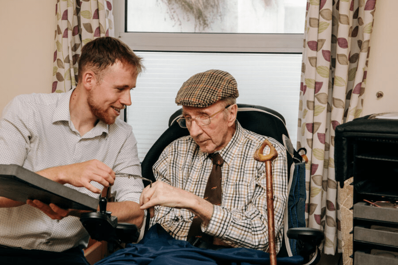 Optometrist, Sam Westoby with his patient Eric, showing him some glasses. 