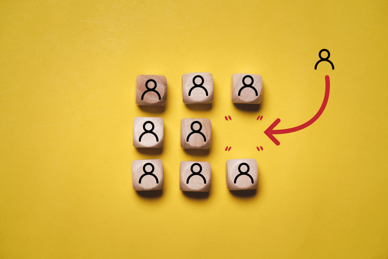 Wooden cubes printed with human icons lined up in rows, with one missing
