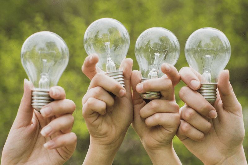 Fyra händer håller glödlampor
