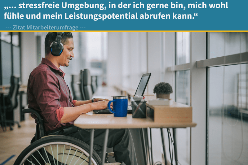 Ein Mann im Rollstuhl arbeitet konzentriert am Laptop in einem hellen Büro. Er trägt Kopfhörer und lächelt leicht. Im Bild: ‚…stressfreie Umgebung, in der ich mich wohlfühle und mein Leistungspotenzial abrufen kann.‘