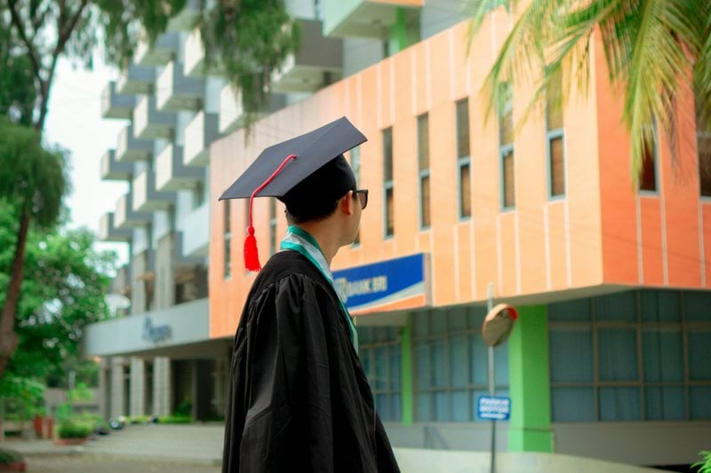 a man in a graduation cap and gown standing in front of a building