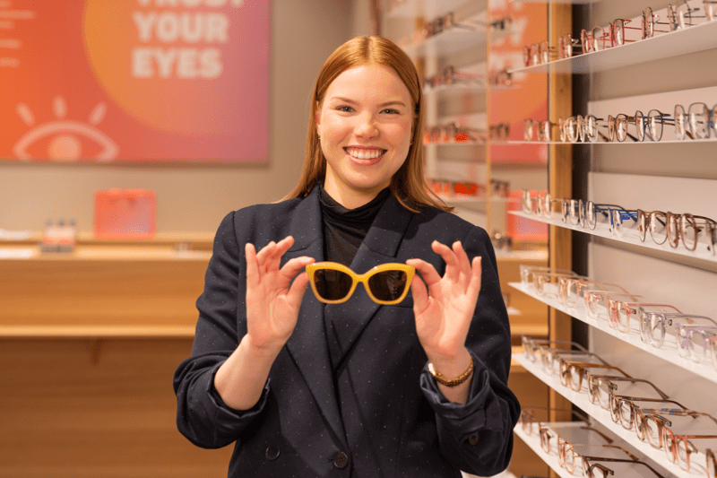 Collega die een bril uit de collectie toont. 