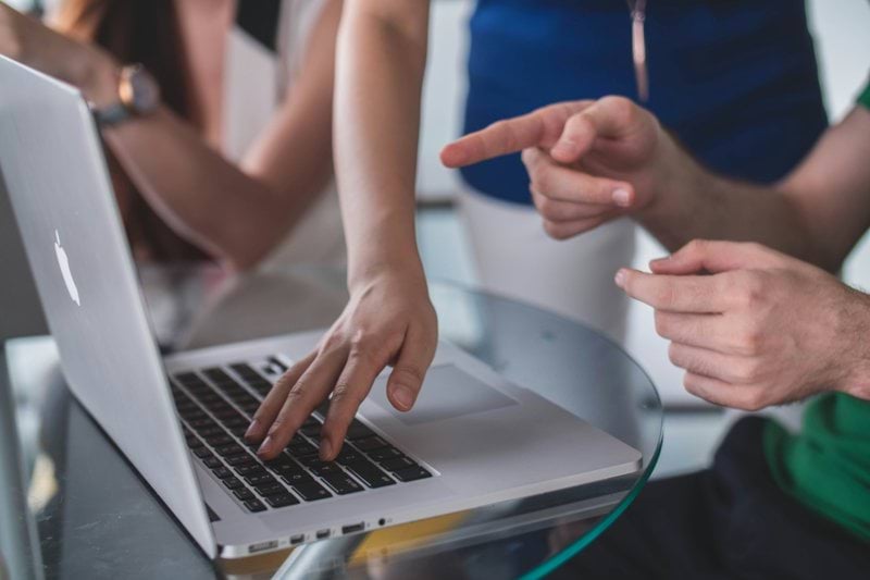 person touching and pointing MacBook Pro