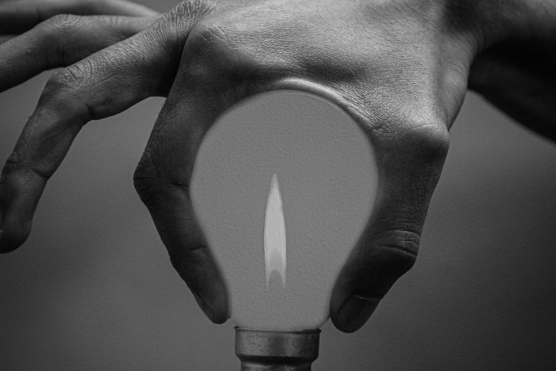 grayscale photo of person holding lighted candle