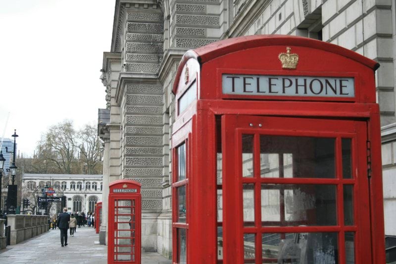 a red telephone booth sitting on the side of a street