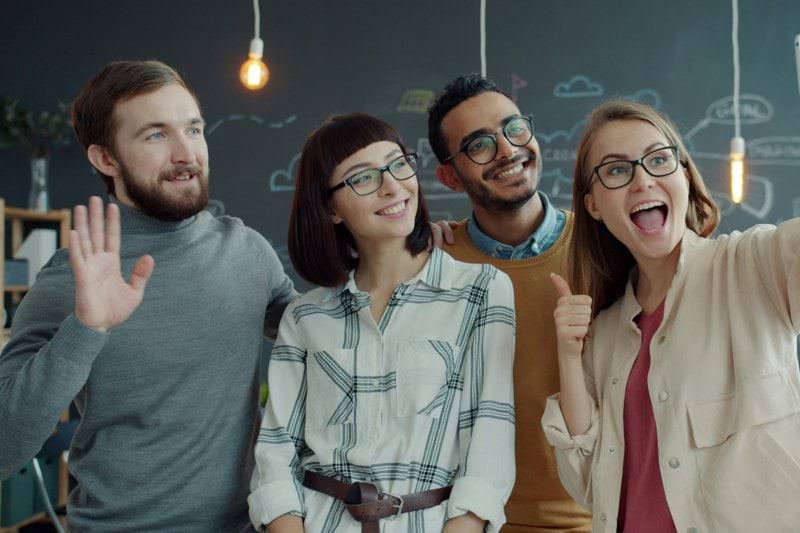 Four friends taking a selfie in a modern office.