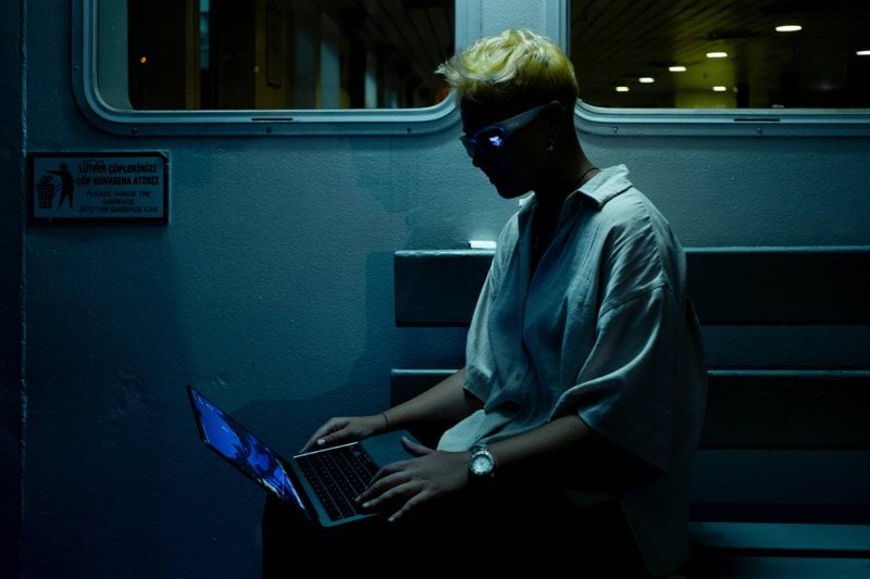 A man sitting on a train using a laptop computer