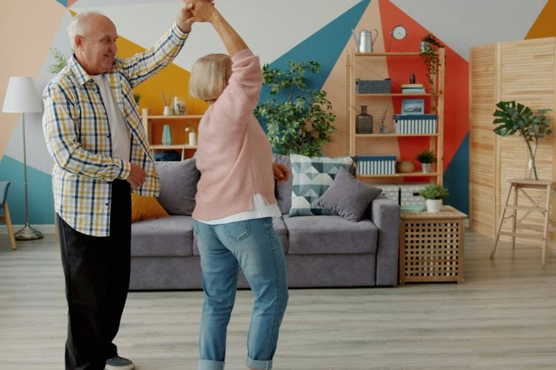 Elderly couple dancing joyfully in a living room