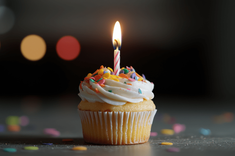 Colourful birthday cupcake with icing and one candle.