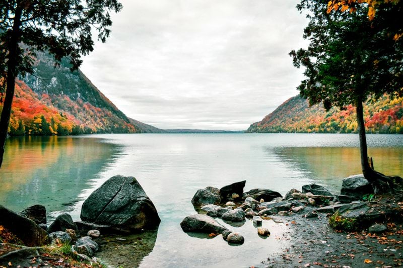 A tranquil lake reflects colorful autumn mountains.