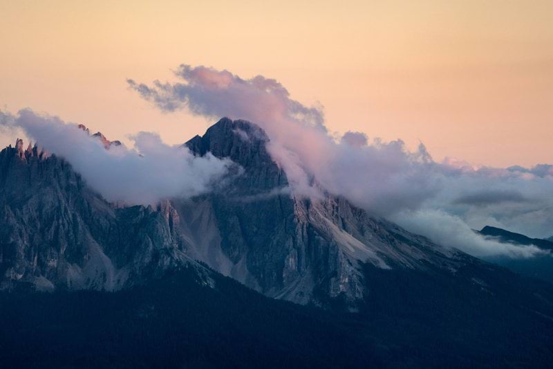 Misty mountain peaks at sunrise with soft pastel sky