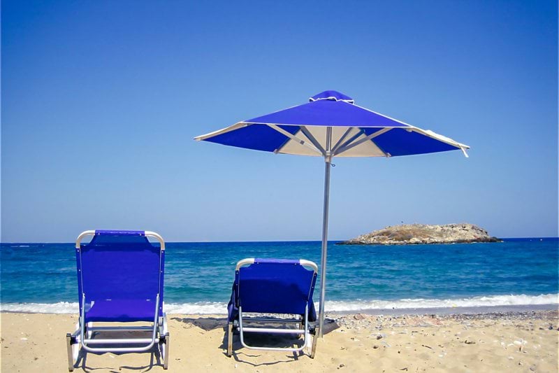 two lawn chairs and an umbrella on a beach