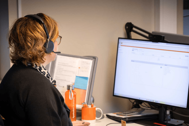 Kvinna med headset jobbar vid sin dator