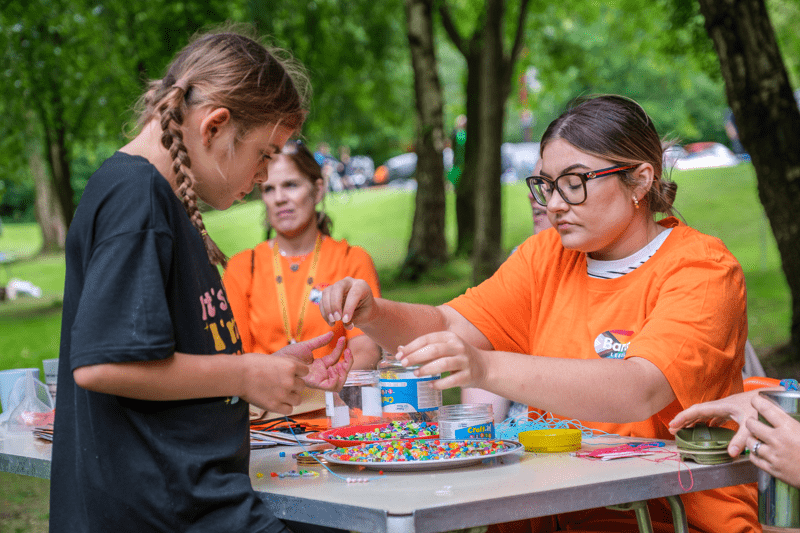 Young person making a bracelet at a Barca-Leeds stall