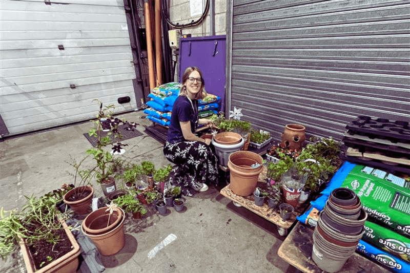 A member of staff taking part in our Gardening Group, potting plants.
