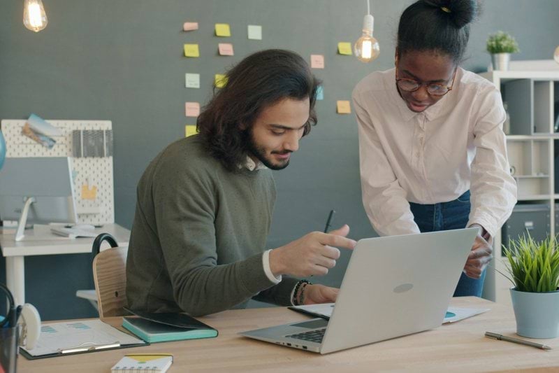 Two colleagues collaborating on a laptop in an office.
