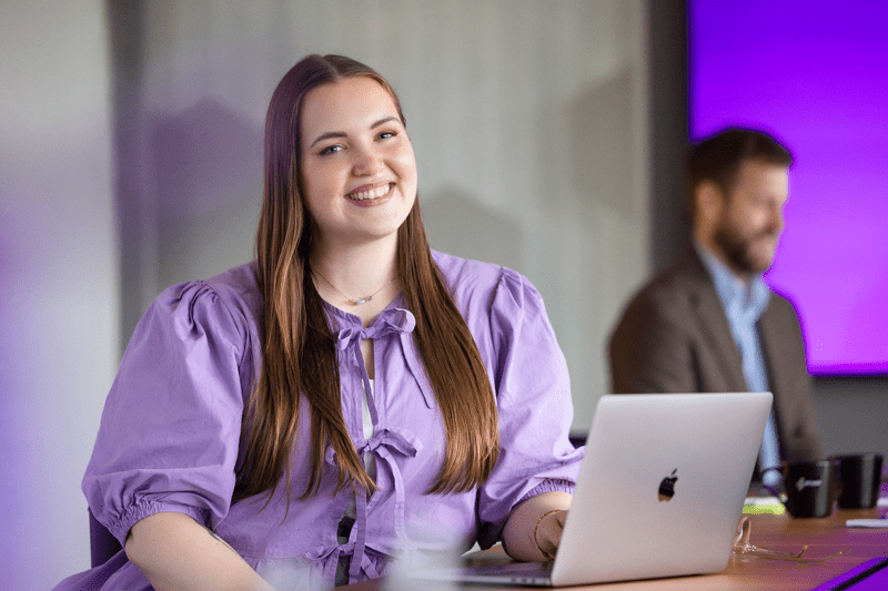 Leende medarbetare framför datorn i ett konferensrum