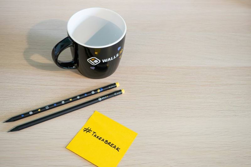 a cup of coffee and two pencils on a table