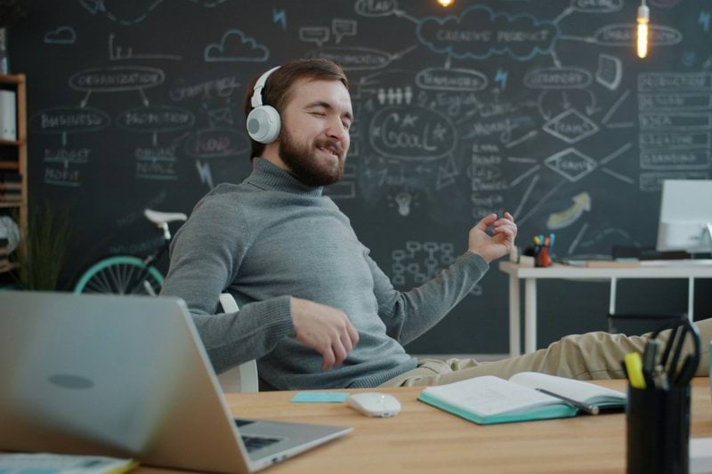 Man with headphones playing air guitar at desk
