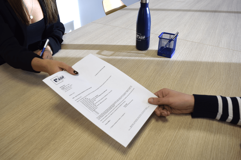 Una persona entrega a un candidato una propuesta de empleo durante una entrevista de trabajo.