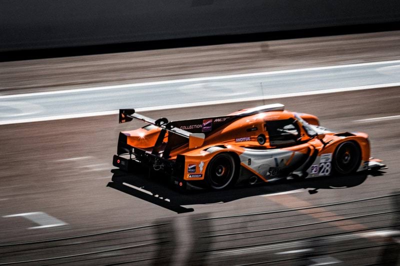 an orange race car driving down a race track