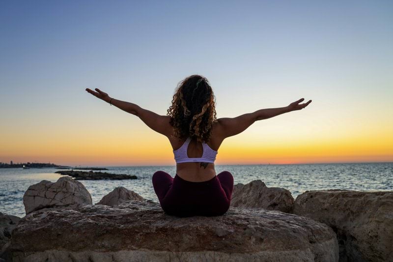 woman sitting on the stone in front of the ocean
