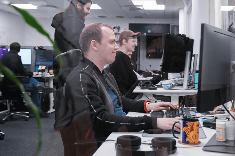 Smiling Game Developers working in collaboration at their desks